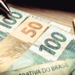 Notas de 100 e 50 reais brasileiras sobre superfície de madeira